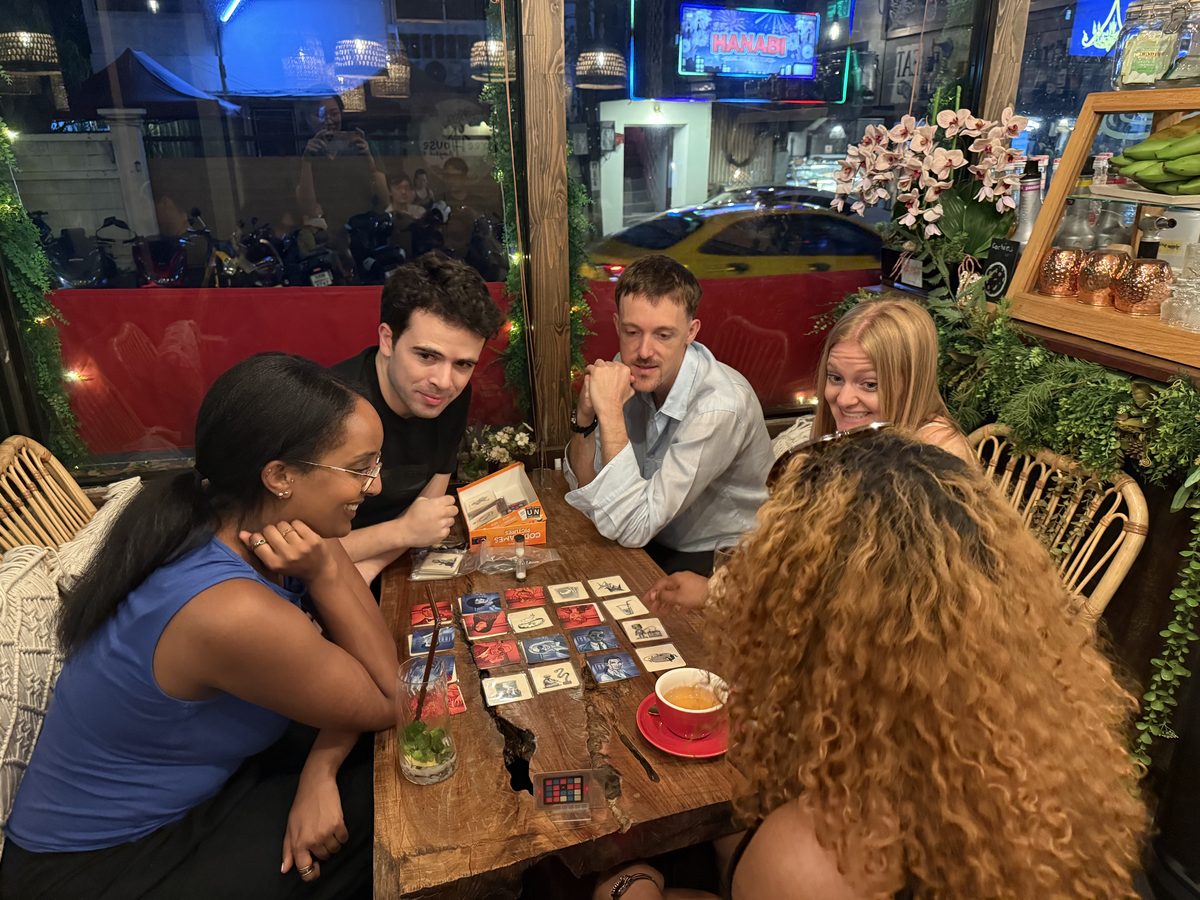 Guests smiling around a table while playing a card-based game.